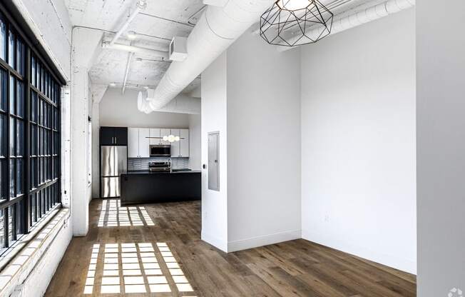 a living room with white walls and a window and a kitchen