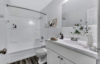 A white bathroom with a toilet, sink, and shower.