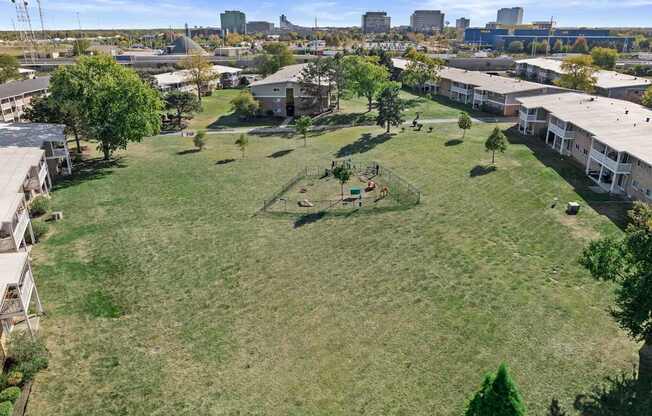 an aerial view of a park with houses and a city in the background