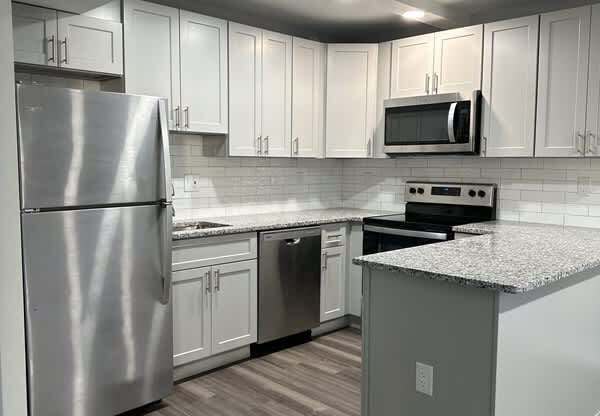 Renovated kitchen with stainless steel appliances and upgraded cabinets, flooring, and counter tops at Stuart Woods* Apartments, Herndon, 20170