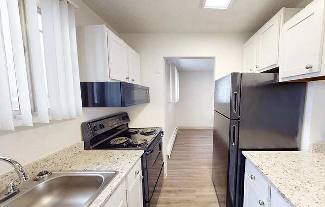 A kitchen with black appliances and white cabinets.