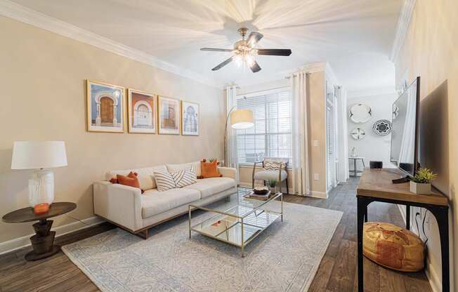 A living room with a white couch, a coffee table, and a ceiling fan.