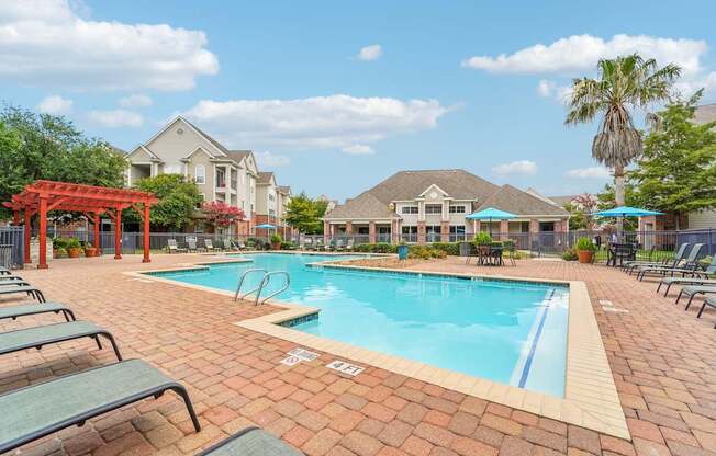 A pool surrounded by lounge chairs and umbrellas.