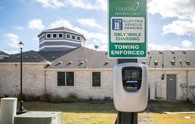 a parking meter in front of a building with a tooting enforced sign  at Orion Prosper Lakes, Texas