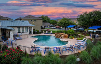 A backyard with a pool and patio furniture.