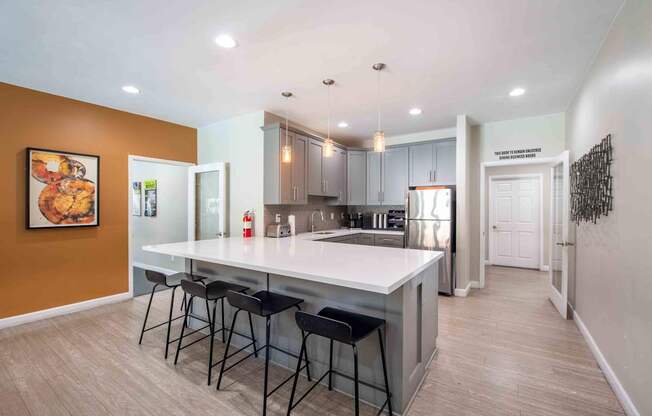 A kitchen with a white countertop and bar stools.