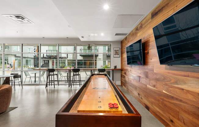 A long wooden table with a shuffleboard game in the middle of it.