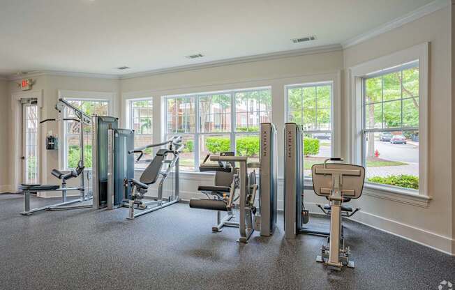 A gym with a variety of equipment including a treadmill, a stationary bike, and a rowing machine.