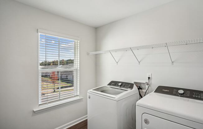 a white laundry room with a window and a white washer and dryer