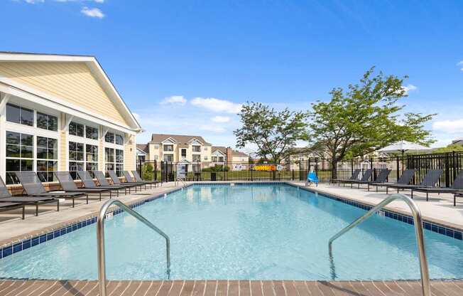 Sparkling swimming pool at Center Point Apartments with surrounding sun deck, lounge chairs, and views of the leasing office and buildings.