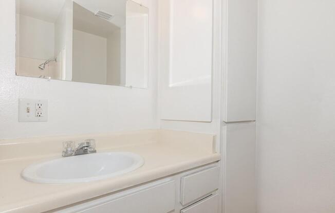 a white sink sitting under a mirror