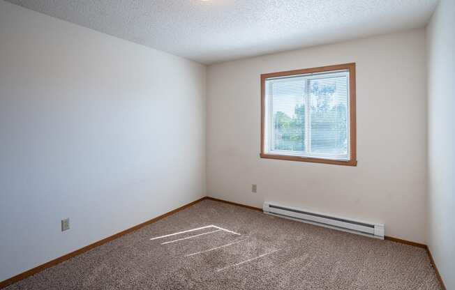 a bedroom with a window and carpeted floors. Fargo, ND Westview Towers Apartments