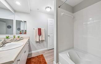 A white bathroom with a white tub and a white sink.
