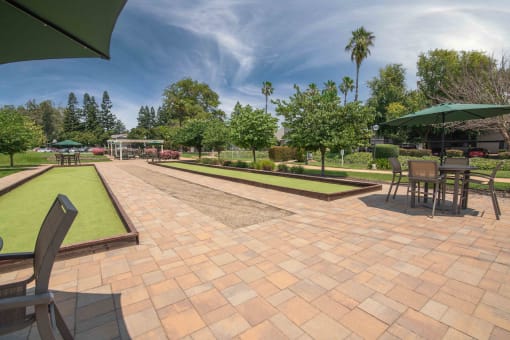 A large patio with tables and umbrellas and bocce call courts