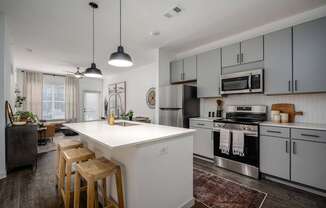 A kitchen with a white island and wooden stools.