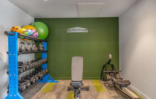 a workout room with a green wall and a workout chair and weights on a shelf