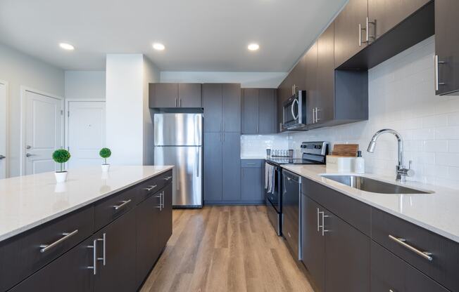 a modern kitchen with dark cabinets and white countertops and a stainless steel refrigerator