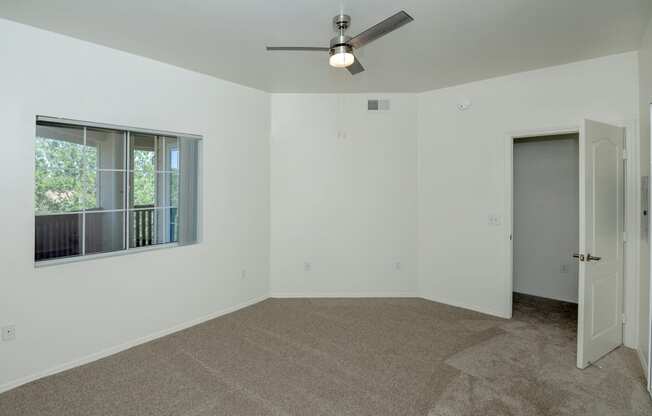 an empty room with a window and a ceiling fan