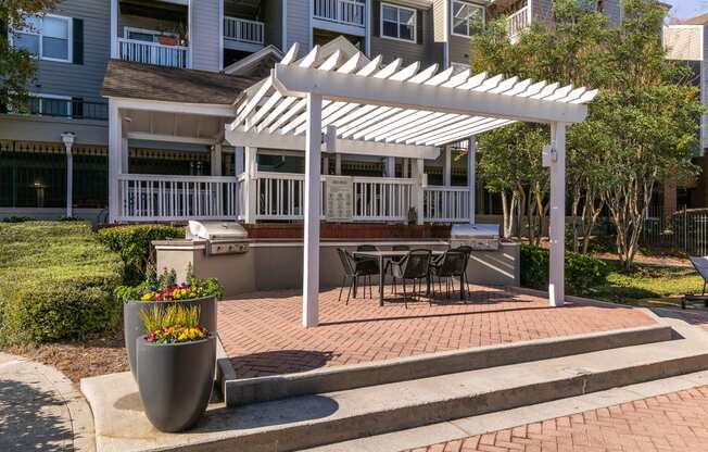 a white pergola on a brick patio with a table and chairs at Briarcliff Apartments, Georgia, 30329
