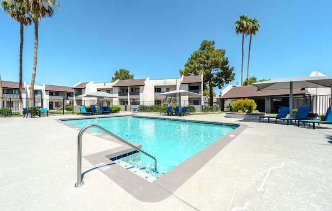 A swimming pool surrounded by palm trees and lounge chairs.