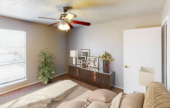 A living room with a couch, a ceiling fan, and a window.