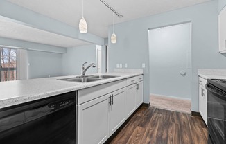 a kitchen with white cabinets and a black dishwasher and a sink