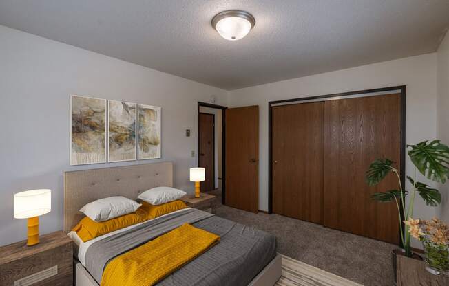 a bedroom with a bed and a closet. Fargo, ND West Oak Apartments