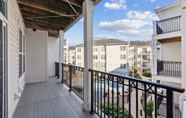 A balcony with a pool in the background.