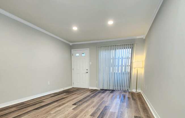 a living room with hardwood flooring and a door to a bedroom