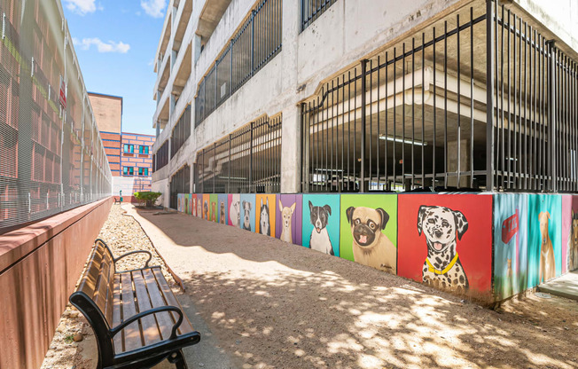 a bench in front of a wall with paintings of dogs on it