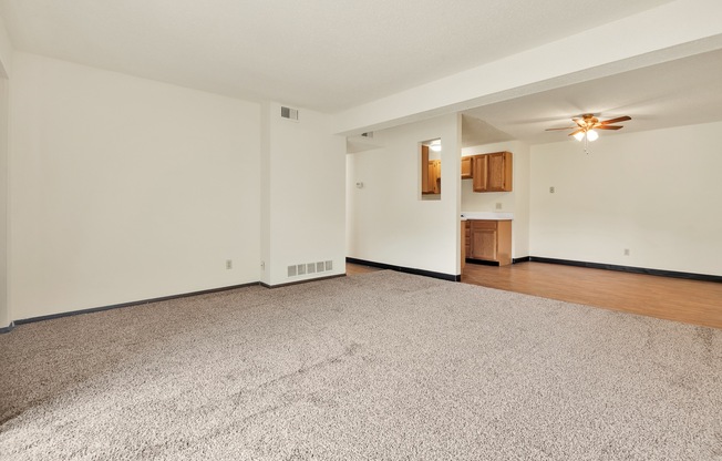 A room with a carpeted floor and a ceiling fan.
