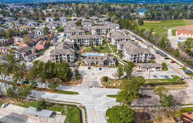 A bird's eye view of a residential area with apartment buildings and a parking lot.