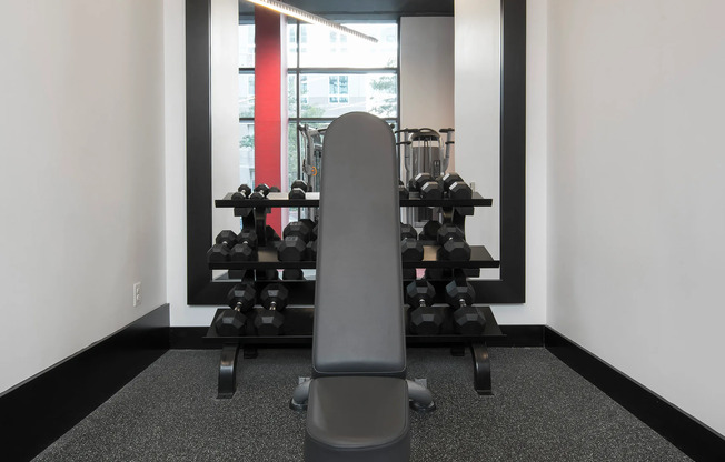 Fitness CenterFitness center at our apartments for rent in Arlington, featuring a bench press stand with free weights.