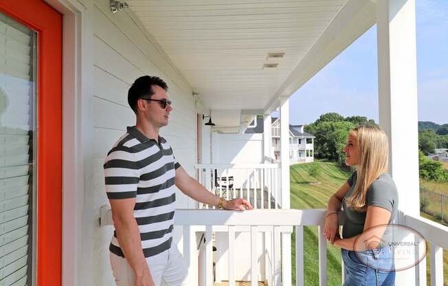 A man and woman standing on the balcony of their apartment home.