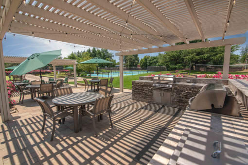 A covered patio with tables and chairs and a grill
