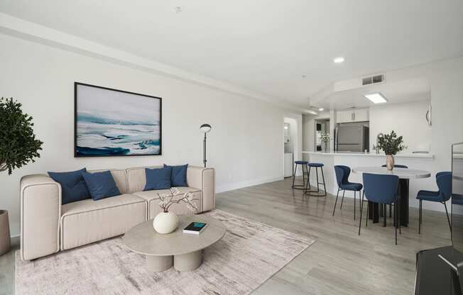 a living room with white walls and a white couch with blue pillows