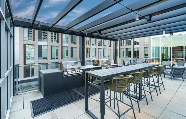 A rooftop grilling area at Modera Pearl with shaded seating and communal tables, designed for hosting meals and casual gatherings above the city.