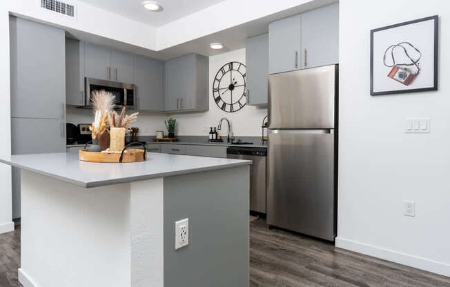 A modern kitchen with a stainless steel refrigerator and a wooden cutting board on the island.