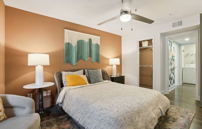 A bedroom with a bed, chair, and two lamps.