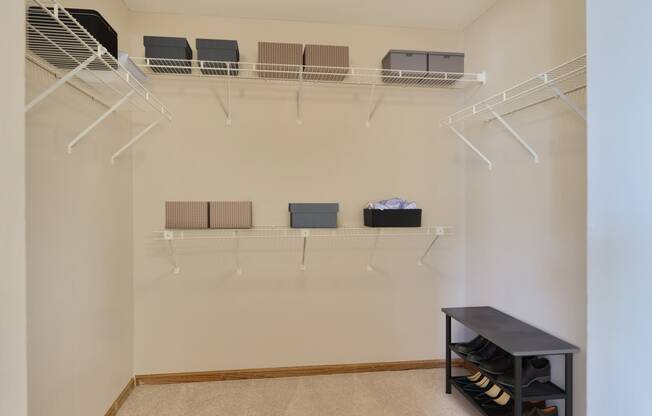 a walk in closet with shelves and a rack on the wall