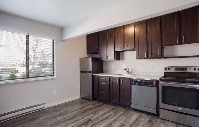 Empty kitchen with wooden cabinets and stainless steel appliances and a window  at Governor's Park, Fort Collins, 80525