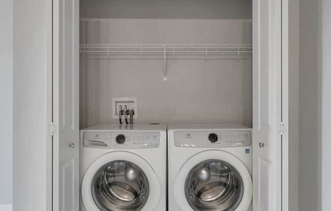 A laundry room with two washing machines and a white door.