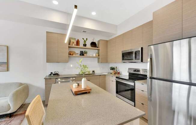 A modern kitchen with a stainless steel refrigerator, a wooden cutting board on the island, and a white chair.