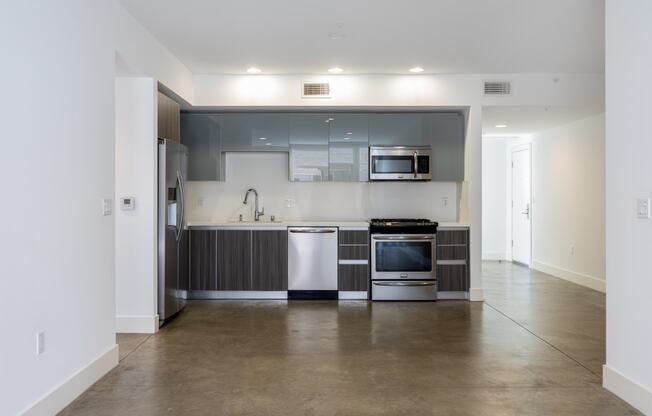 an empty kitchen with stainless steel appliances and white walls