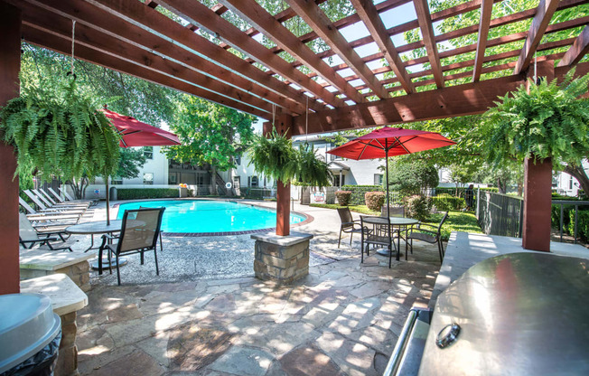 a backyard with a pool and a covered patio with umbrellas