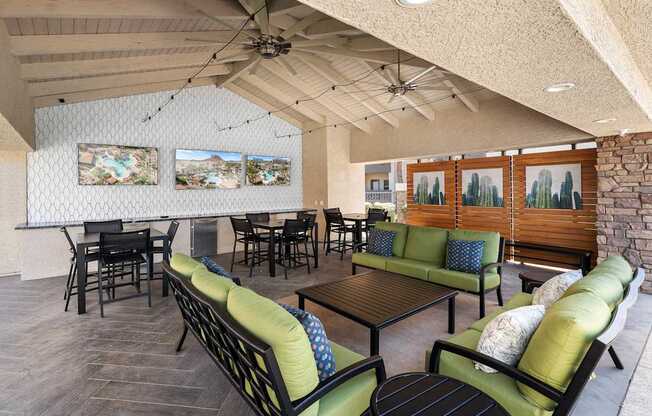 A room with a ceiling fan and a long couch with green pillows.