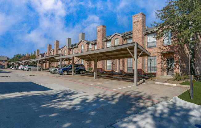 A parking lot in front of a brick building with a canopy.