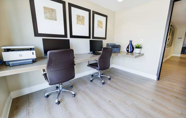 a home office with two desks and two chairs and a printer