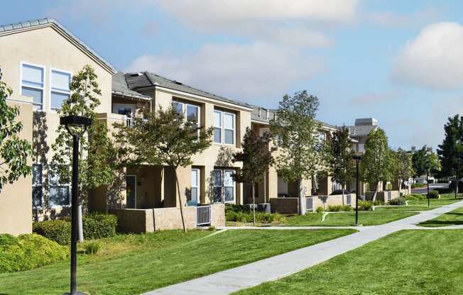 a row of apartments on a sidewalk with grass and trees