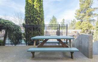 a picnic table in a park with a fence and trees